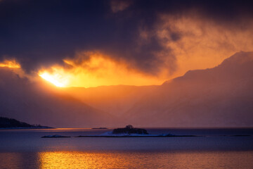 Obraz premium A beautiful small island in the Norway fjords during snowy winter day. Arctic nature in Scandinavia during winter season.