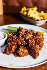 Korean BBQ Chicken Wings on white plate in restaurant with blue cheese dip and celery