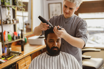 In a chic salon setting, a barber skillfully and meticulously trims the hair of a stylish client...