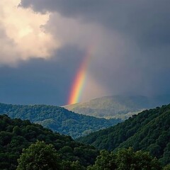 Mountaintop rainbow descends through stormy clouds over lush evergreen forest , beautiful, blue