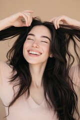 Fototapeta premium Smiling young woman with long dark hair playing with her hair, joyful expression, natural beauty, indoor portrait, emotional wellness, personal care lifestyle.