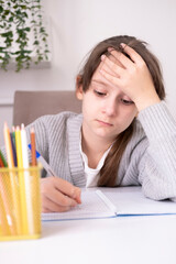 Tired, frustrated student is sitting at desk doing his homework. Learning difficulties, the concept...