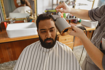 A gentleman is currently having his hair styled and groomed in a modern and contemporary barber...