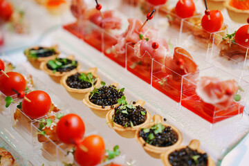 different canapes in cups with sauce and tartlets with black caviar. Convenient and beautiful serving of appetizers at a buffet table. catering at events.