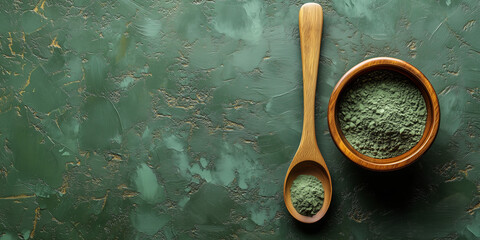 Green spirulina algae powder on a wooden spoon and bowl on green rustic surface