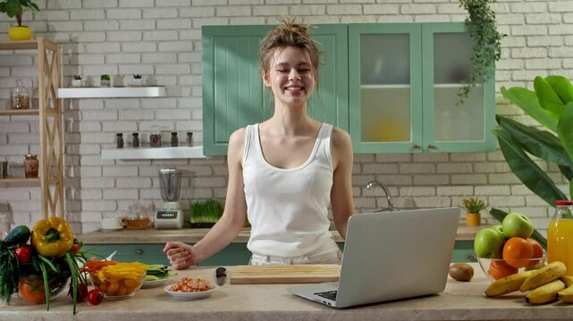 Young woman at the table in the kitchen preparing spring rolls for healthy lunch, woman foodie blogger talking at camera, showing ingredients for snack. Slow motion.