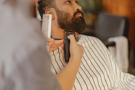 In a colorful, stylish salon setting, a skilled barber expertly trims and shapes a clients beard with care