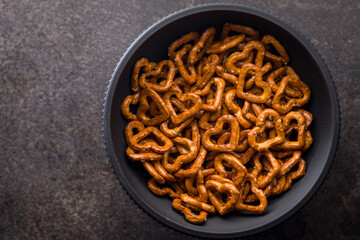 Heart shaped pretzel in bowl on black table. Top view.
