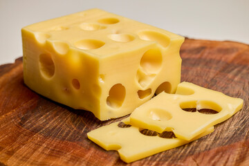 a piece of emmental cheese on a wooden chopping board