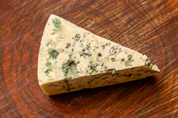 a piece of dorblu cheese on a wooden chopping board
