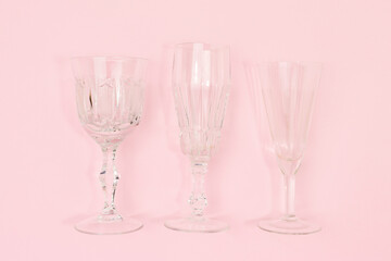Three vintage crystal glasses on a pink background. Minimal composition.
