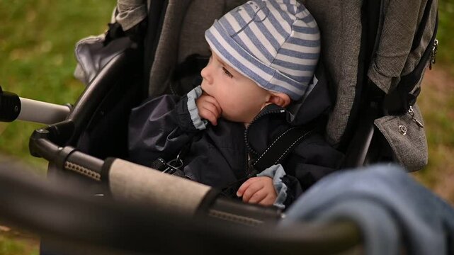8 month old baby sitting in a stroller in the park, smiling and laughing, happy childhood concept