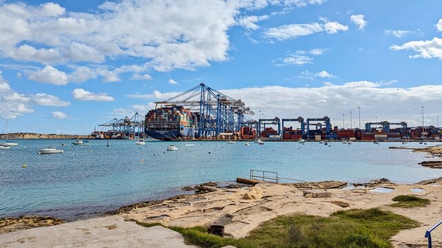 Busy waterfront showcases massive cranes above freeport brimming with stacked containers, freeport fostering global trade expansion: Birzebbuga, Malta - 01.12.2024