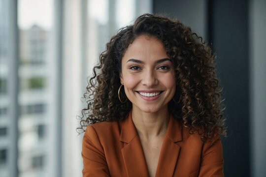Close up photo portrait of beautiful Latin American woman with curly hair , businesswoman inside office building smiling and looking at camera.