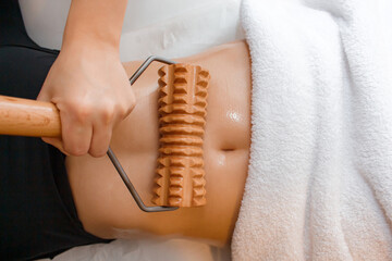 Gentle abdominal massage technique using a wooden roller in a calming wellness setting	