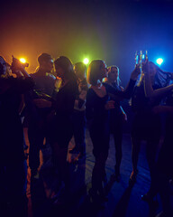 Holidays celebration. Young people attending nightclub, party, cheerfully dancing under neon lights, having fun and relaxing. Concept of youth culture, leisure, enjoyment