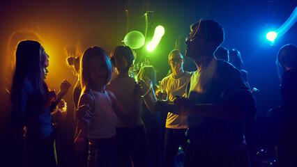 Group of cheerful young people celebrating together in vibrant neon-lit club with colorful neon lights. Joyful and carefree atmosphere, highlighting bond and fun. Concept of youth culture
