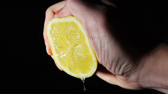 homemade lemonade hand squeezing juice from lemon slowly. freshly squeezed lemon juice on a black background 120 fps