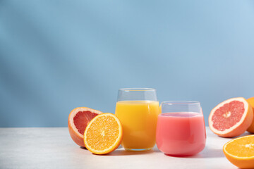 Orange and grapefruit refreshing drink on blue background. Smoothie, juice or citrus cocktail side view