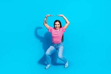 Happy young woman in casual striped outfit posing against a bright blue background, showcasing a joyful attitude