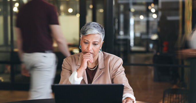 Business woman, serious and thinking on computer, reading email and decision, choice or marketing report in busy office. Manager for online risk, planning or doubt on laptop with analysis or research