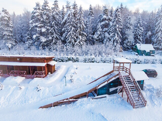 Winter wooden slide near a snowy forest