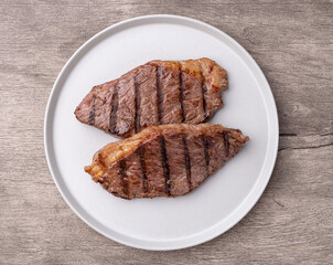 Grilled picanha beefs in a plate over wooden table