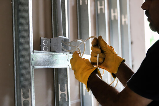 
Worker carrying out an electrical installation in a house made of steel frame
