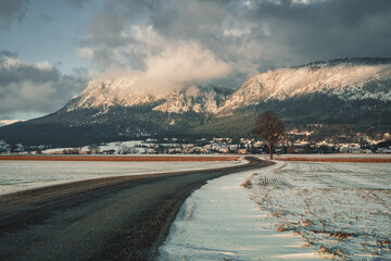 small snowy winter road with Mountains in the background