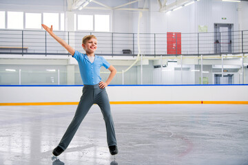 A young boy figure skater skates on the ice of an indoor ice arena