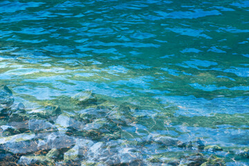 Blue water with ripples on the surface. Defocus blurred transparent blue colored clear calm water surface texture with splashes and bubbles. Water waves with shining pattern texture background.