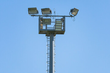 Bright lights illuminate the field under a clear blue sky