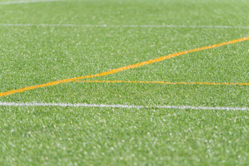 Bright green grass field with crisp white and orange markings in sunlight