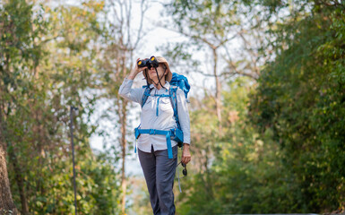 Senior woman is hiking outdoors, enjoying nature expression looks into the distance observing and possibly guide trekking and trail ecotourism adventure concept.