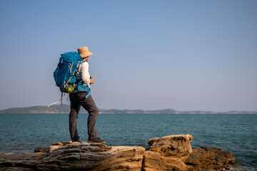 Senior woman is hiking outdoors, enjoying nature expression looks into the distance observing and...
