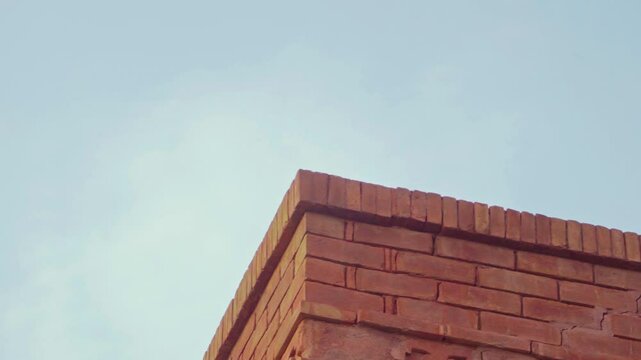 Sharp corner of a red brick building standing against a clear blue sky.