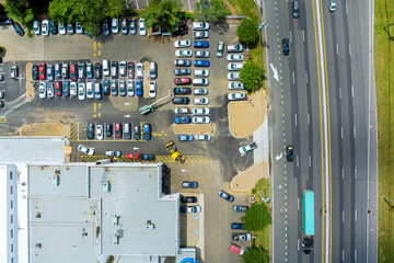 Cars are parked in lot adjacent to commercial building while traffic flows along road near American...