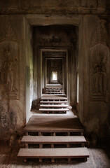 Exploring the ancient corridors of Angkor Wat in Cambodia, revealing intricate carvings and weathered architecture at dusk