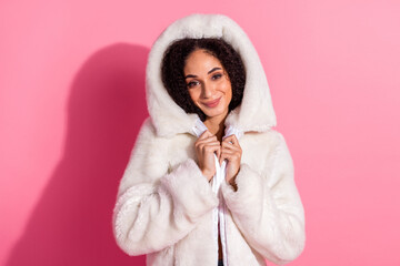 Portrait of a cheerful young woman in a stylish white jacket against a vibrant pink background,...