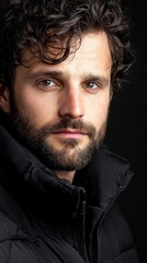 Fototapeta premium A man with a beard and glasses is wearing a black jacket