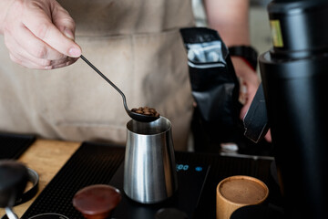 barista carefully measures coffee beans into metal container, preparing for brewing. scene captures precision and dedication involved in crafting perfect cup of coffee