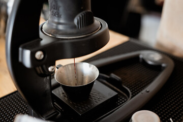 manual espresso machine brewing fresh coffee into metal cup, showcasing process of making espresso with precision and care. setup includes scale for accurate measurement, emphasizing art of coffee