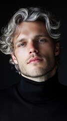 Fototapeta premium A man with a beard and a ponytail is wearing a black shirt and a black sweater