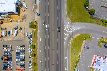 Traffic moves steadily on wide road, surrounded by commercial buildings, parking areas in American...