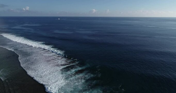Drone view over splashing waves moving on the body of sea wayer with cloudy sky on the horizon