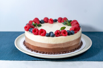Three chocolate cake with raspberries and blueberries.