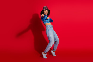 Young stylish woman in trendy casual attire posing joyfully on red background showcasing modern fashion and energetic style