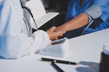 Doctor using sphygmomanometer with stethoscope checking blood pressure to a patient in the hospital.