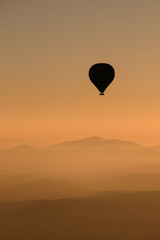 Silhouette hot air balloon at sunrise, mountains in background