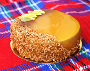 Mousse cake with orange mirror glaze, blackcurrant filling, decorated with lemon slices and coconut flakes.